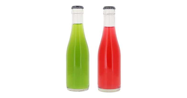 Two glass bottles of beverages coloured with natural colours. The first glass bottle is a lime green, the second is a bright red.